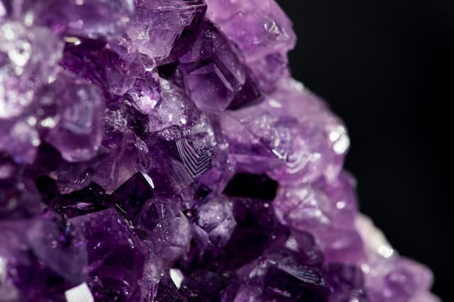 Karanlık zemin üzerinde mor amethyst kristali kümesi, yakın plan